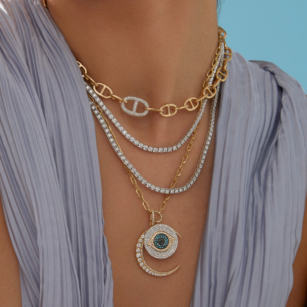 Model wearing diamond tennis necklaces, anchor chain link necklace, gold chain link necklace with diamond evil eye and moon charm